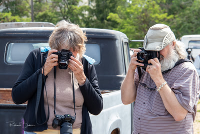 Two photographers examine results by looking in their cameras.