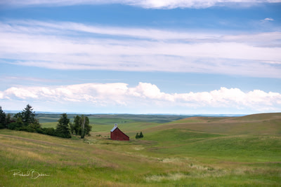 Red Salt Box barn in field under cloudy sky.